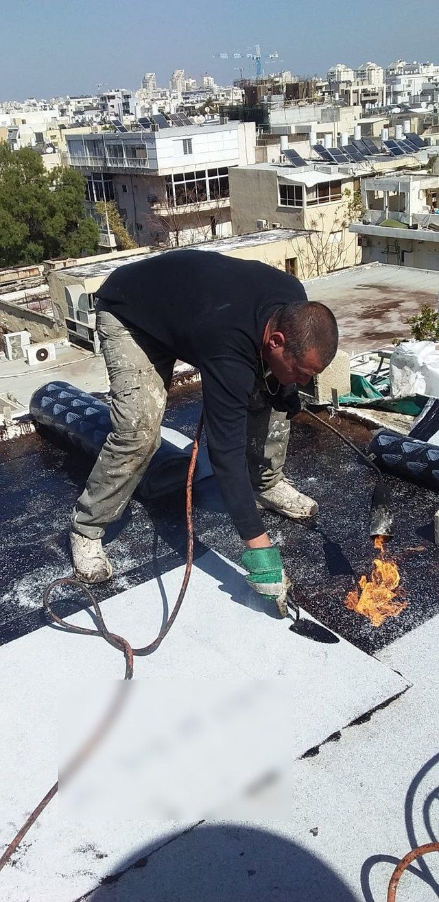 שרון רכון על הגג ומלחים את שולי היריעה, להבת המבער נראית בצד הימני של הפריים